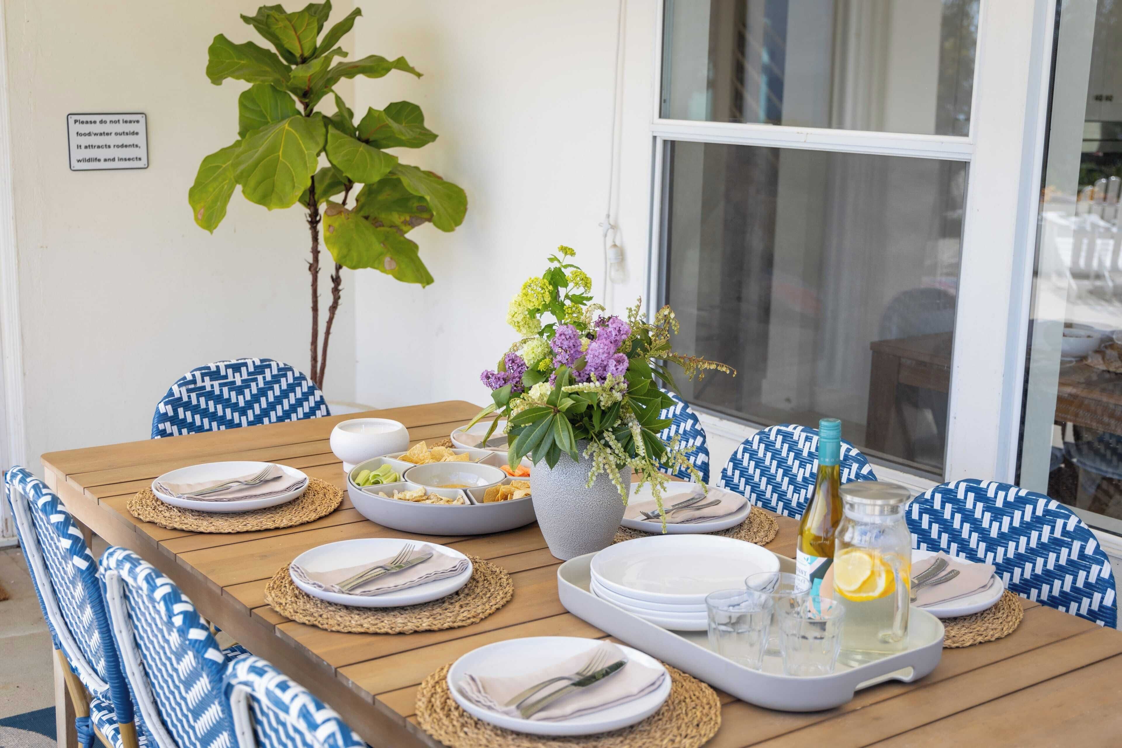 A dining table set with plates, cutlery, and a vase of flowers.