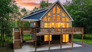 A two-story cabin with a balcony, a staircase, and a deck. - Bluejay Getaway by Avantstay Private Lake Cabin Hot Tub + Game Room Walk to Lake (Albrightsville)