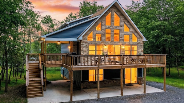 A two-story cabin with a balcony, a staircase, and a deck.