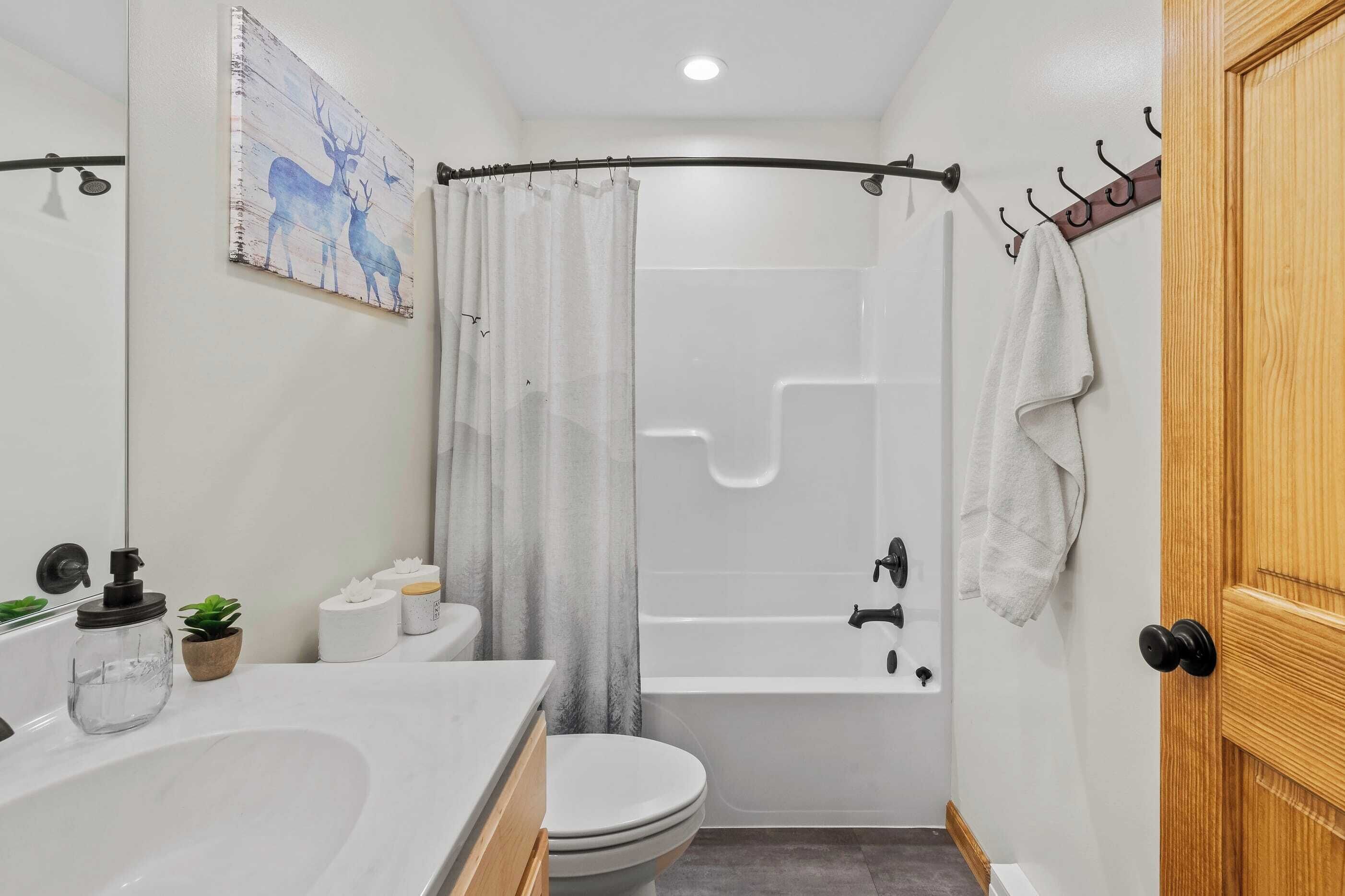 A bathroom with a bathtub, toilet, sink, and a shower curtain.