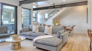 A modern living room with a grey sectional sofa, a coffee table, and a staircase leading to a dining area. - The Ridge at Canyons Village by Avantstay Stunning Slope-side Condo w/ Hot Tub (Park City)