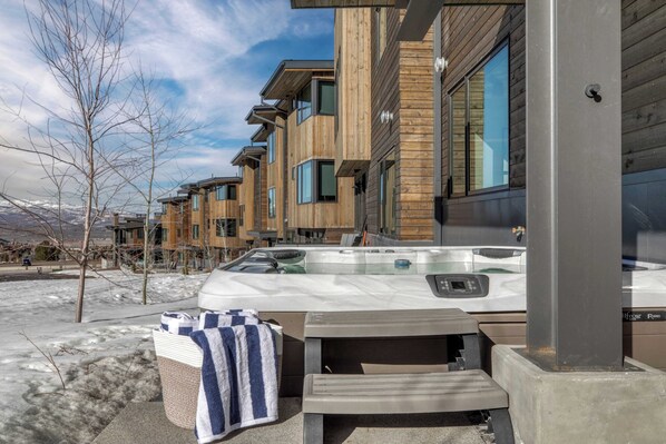 A spa area with a hot tub, a towel, and a wooden building in the background.