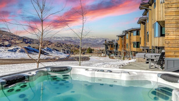 A hot tub area with a view of a wooden building and a snowy landscape. - The Ridge at Canyons Village by Avantstay Stunning Slope-side Condo w/ Hot Tub (Park City)