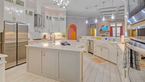 A modern kitchen with white cabinetry, stainless steel appliances, and a central island. - Graford by Avantstay Hot Tub, Firepit, Mini Putt (Corpus Christi)