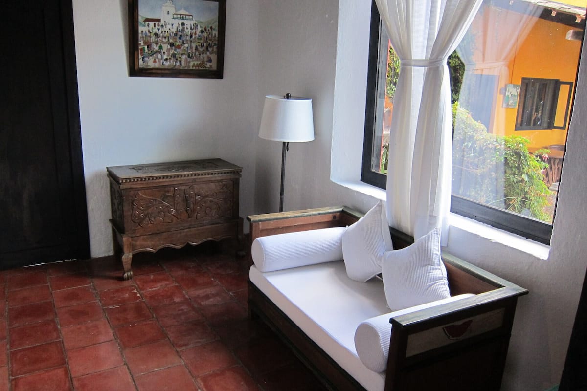 Un dormitorio pequeño y ordenado, con cama, mesita de noche, lámpara y cómoda.
