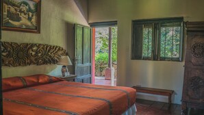 Un dormitorio con una cama grande, un cabecero de madera, un banco, una ventana y una puerta que da al exterior.