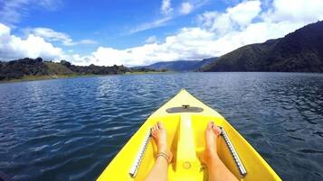 Un kayak sur une eau calme, sous un ciel dégagé, avec des collines qui se dessinent à l'horizon.