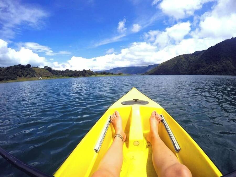 Un kayak sur une eau calme, sous un ciel dégagé, avec des collines qui se dessinent à l'horizon.