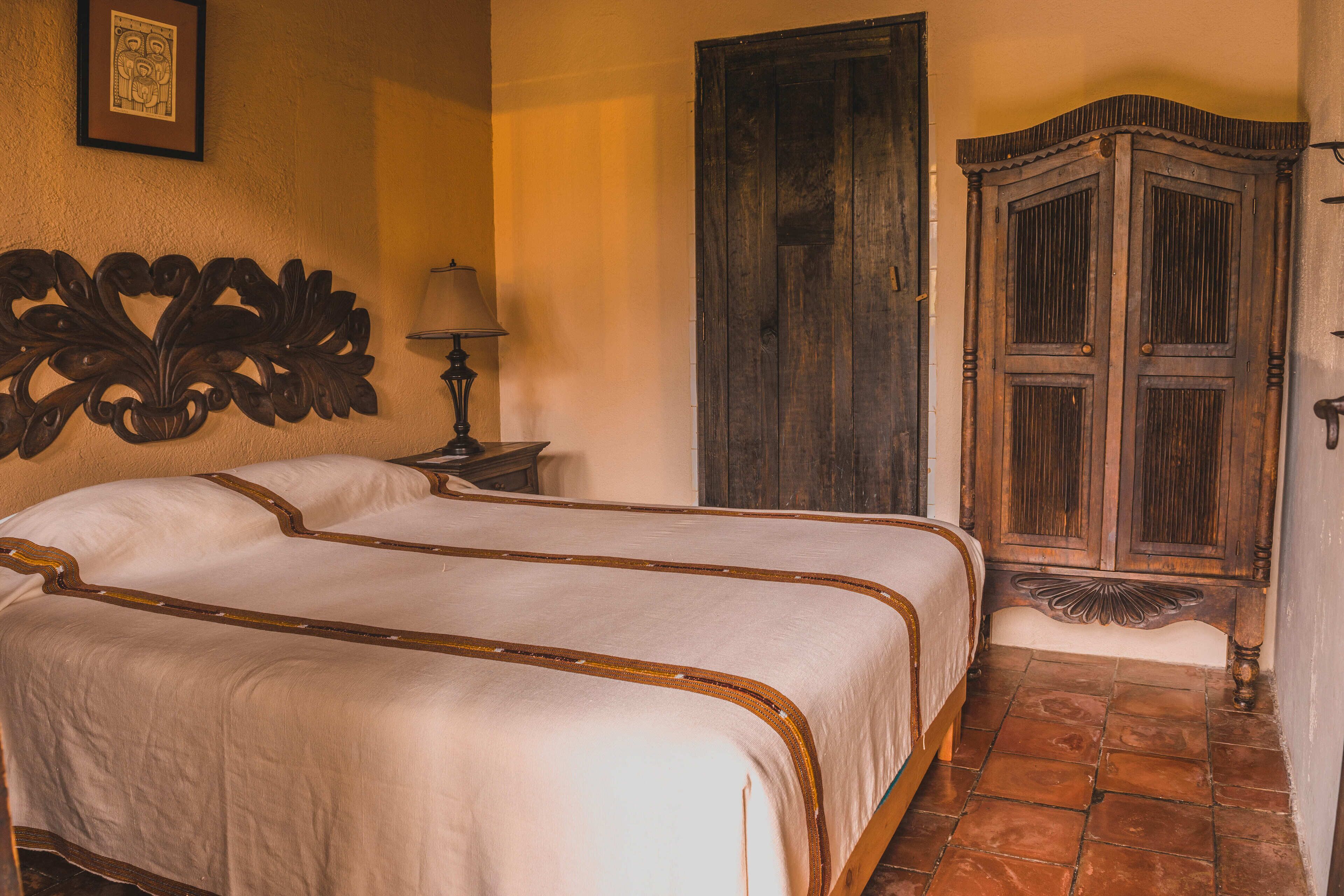 Un dormitorio con una cama grande, un armario de madera y una mesita de noche con una lámpara.