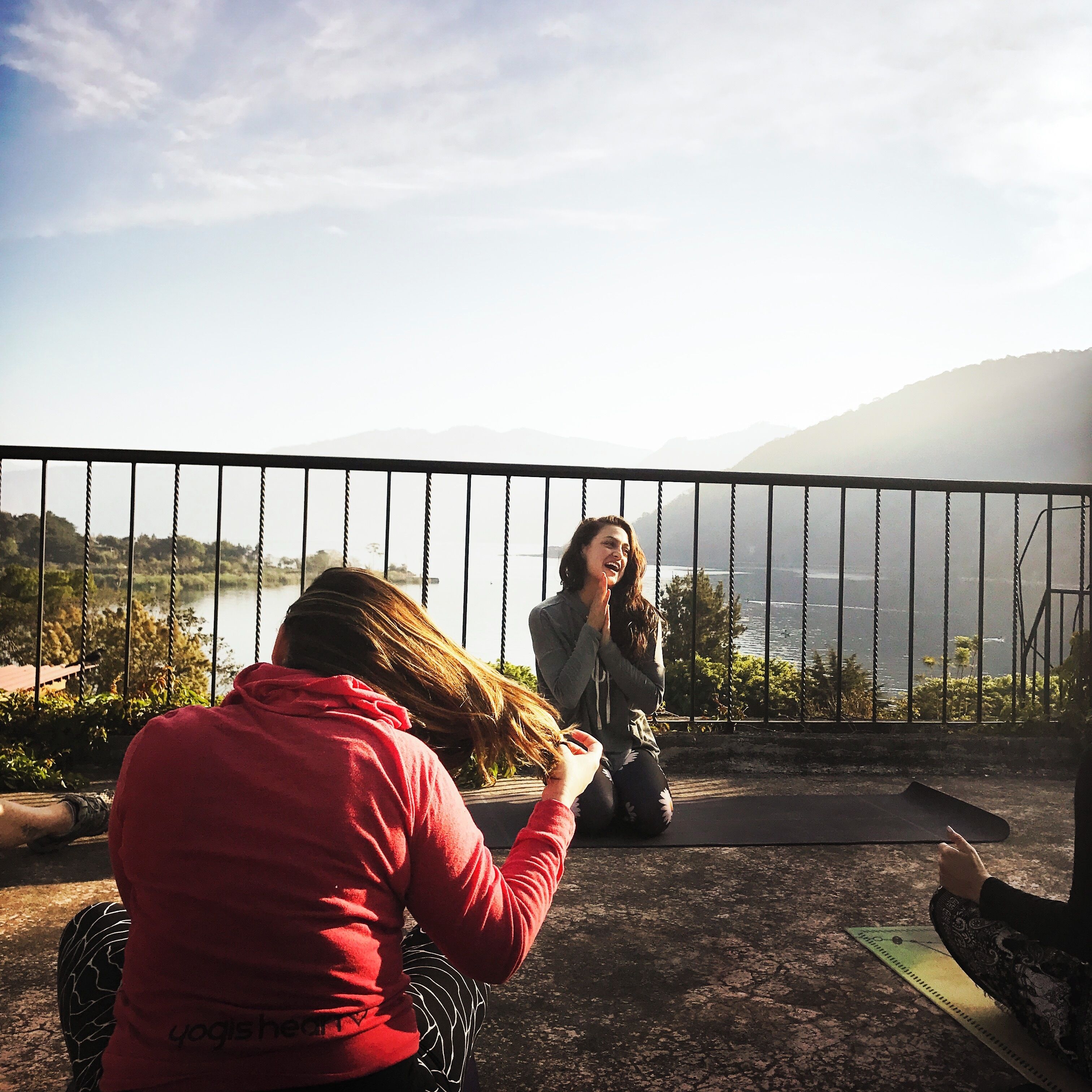 A person sitting on a swing overlooking a lake with mountains in the background.