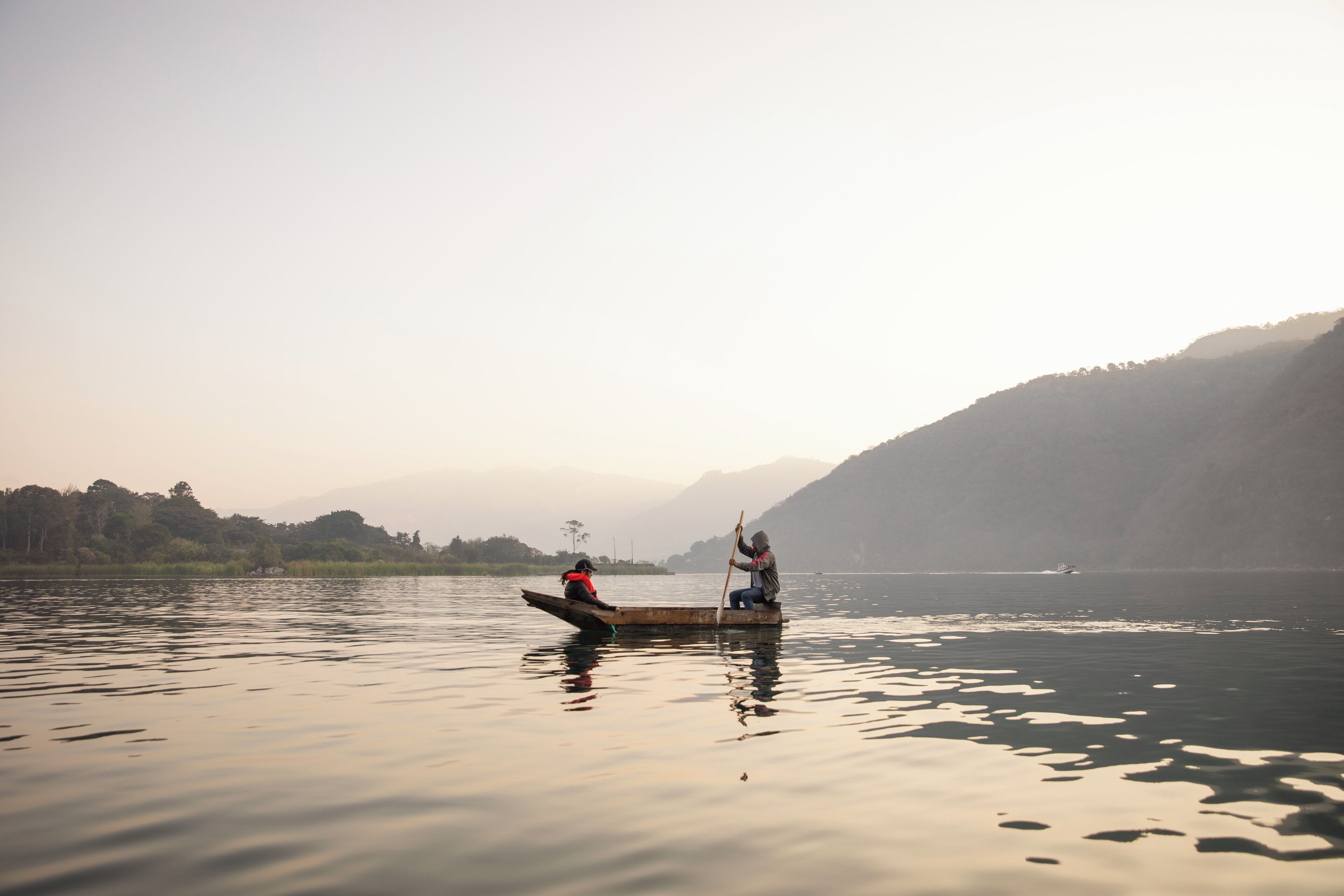 A calm lake with a boat carrying two people.