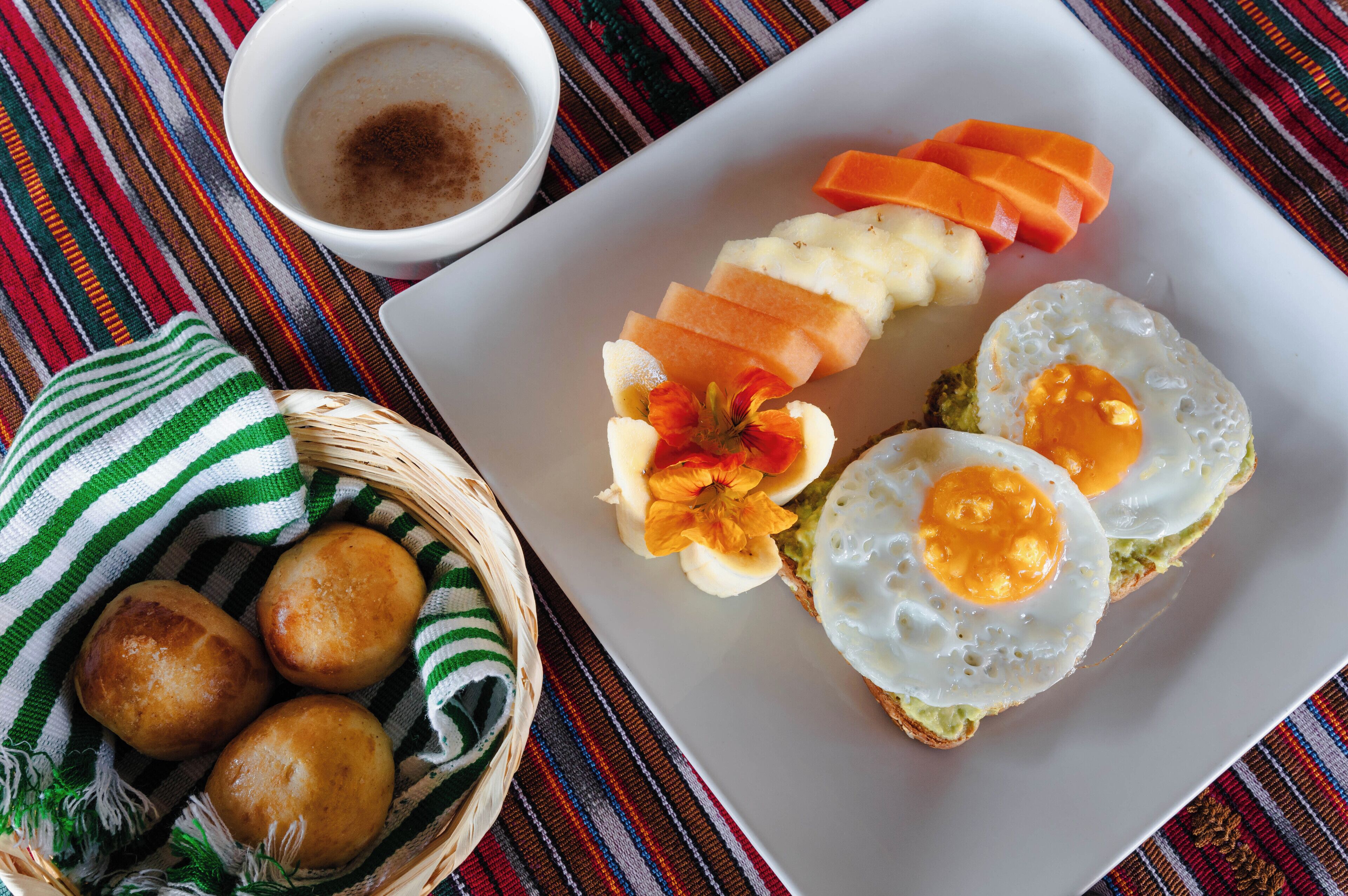 A plate with eggs, avocado, and sliced carrots.