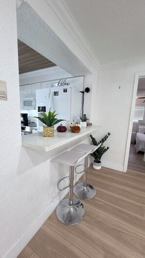 A modern kitchen with a white refrigerator, a sink, and a countertop with decorative pumpkins.