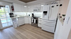 Una cocina moderna con armarios blancos, electrodomésticos de acero inoxidable y un microondas integrado.