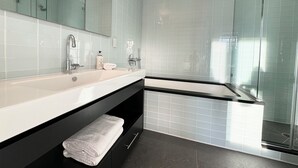 A modern bathroom with a large mirror, a white sink, a black vanity, and a glass shower enclosure. - 2 bed/2 bath luxe condo in Midtown  (New York)