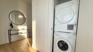 A laundry room with a Bosch washing machine, a mirror, and a metal shelf unit. - 2 bed/2 bath luxe condo in Midtown  (New York)