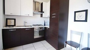 A modern kitchen with dark cabinetry, a stainless steel stove, and a framed picture on the wall. - MDS 3 - My Home in Como (Muronico)