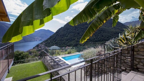 A pool area with a view of mountains and a lake, surrounded by greenery and a stone wall. - MDS 3 - My Home in Como (Muronico)