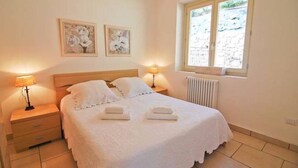 A bedroom with a bed, two bedside tables with lamps, a radiator, and two framed pictures on the wall. - MDS 3 - My Home in Como (Muronico)