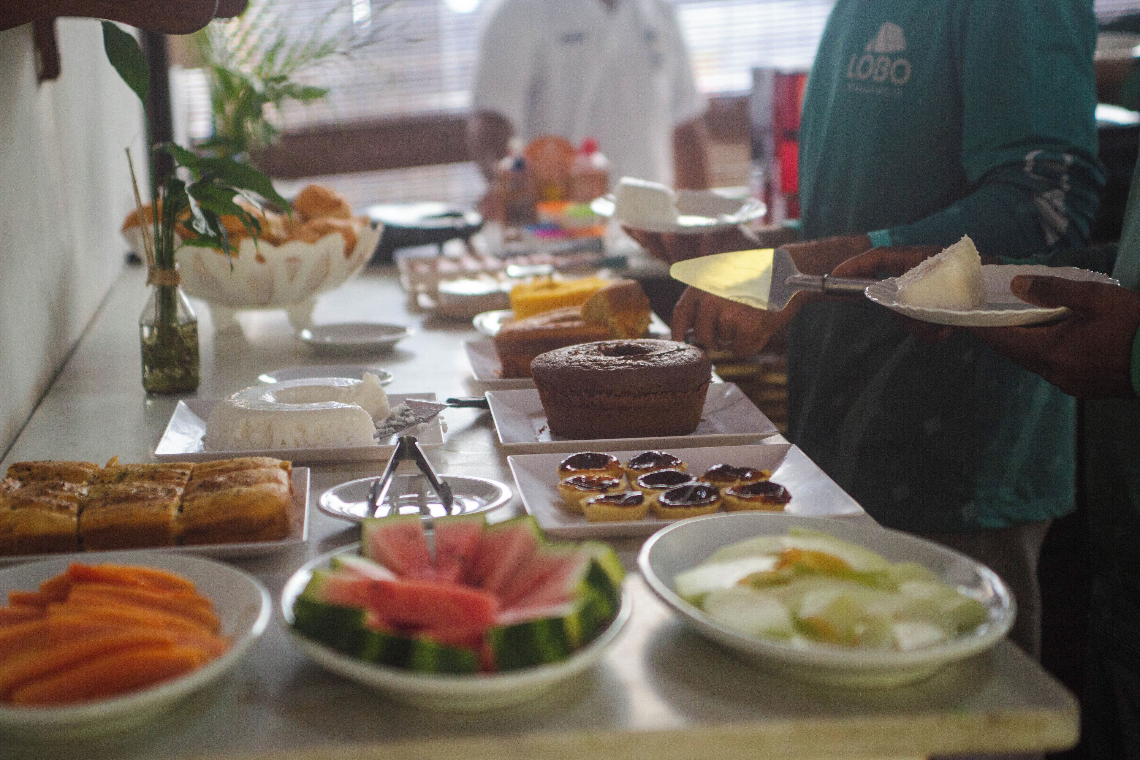 Una mesa de buffet con diferentes opciones de comida, incluyendo pasteles, frutas y postres.