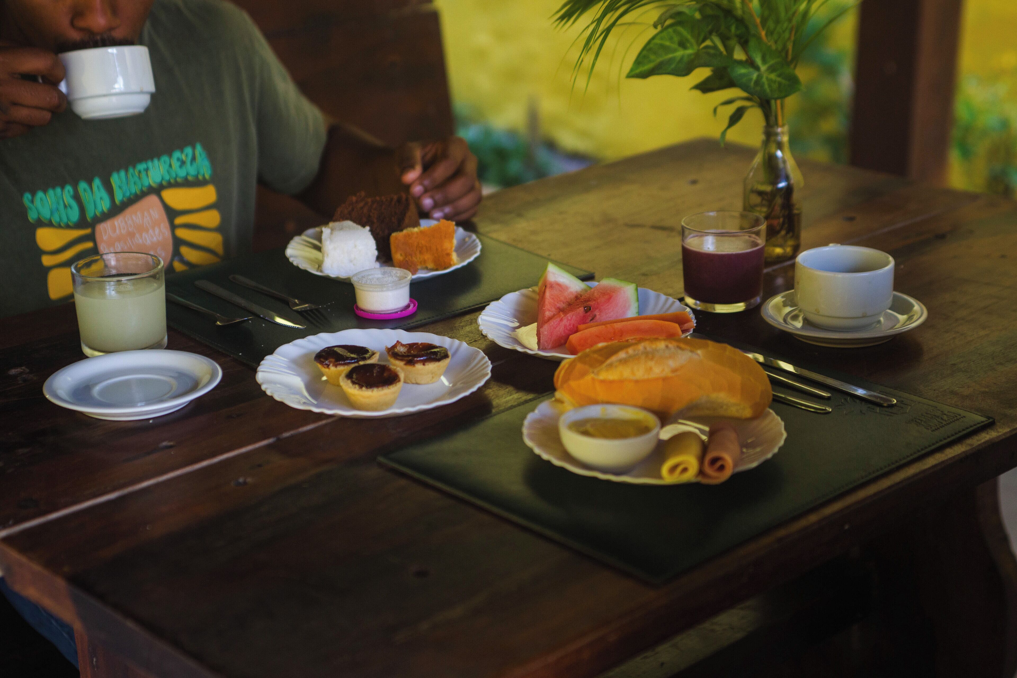 Une table en bois sur laquelle on trouve divers aliments, notamment des pâtisseries, un sandwich et un verre contenant une boisson.