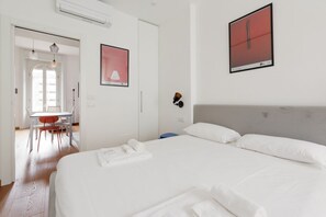 A hotel room with a bed, a desk, a chair, and a framed picture on the wall.