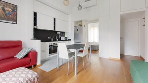 A compact living space with a kitchenette, dining area, and a red sofa. - GuestHost - Buschi Milano-Città Studi Apartment (Milano)