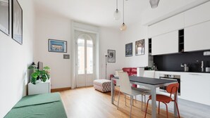 A modern kitchen with white cabinets, a dining table with chairs, a bench, and a door with a view. - GuestHost - Buschi Milano-Città Studi Apartment (Milano)