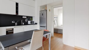 A modern kitchen with white cabinets, a black countertop, a microwave, and a refrigerator. - GuestHost - Buschi Milano-Città Studi Apartment (Milano)