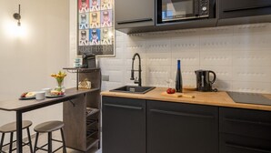 Une cuisine moderne équipée d’un four à micro-ondes encastré, d’un évier et d’un coin bar avec des tabourets.