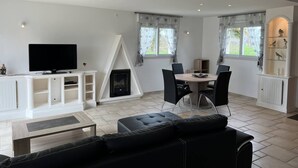 Una sala de estar moderna con televisor de pantalla plana, chimenea, comedor con sillas y sofá de cuero negro.