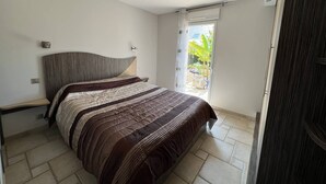 Un dormitorio con cama, cabecera, ventana y puerta.