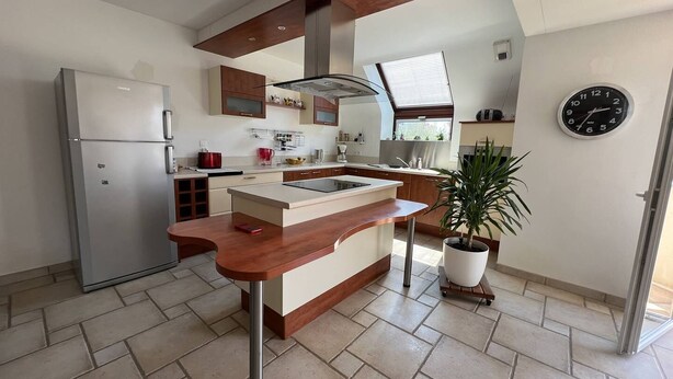 Una cocina moderna con una isla central, un refrigerador y un reloj en la pared.