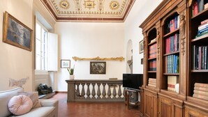 A room with a sofa, a television, a bookshelf, and a decorative ceiling. - Santo Spirito Frescoed 6 sleeps apartment (Firenze)