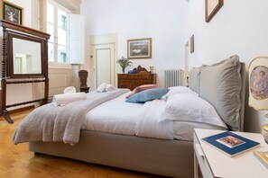 A bedroom with a bed, a dresser, a mirror, and a window.