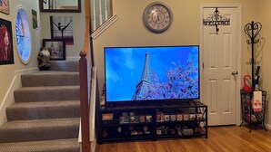 A staircase leading to a landing with a flat-screen TV displaying the Eiffel Tower, a welcome sign, and a coat rack with umbrellas. - Lovely home in good location just few minutes to OleMiss and downtown.  (Oxford)