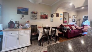 A cozy living room with a red sofa, a dining table with chairs, and a kitchen area with cabinets and a coffee maker. - Lovely home in good location just few minutes to OleMiss and downtown.  (Oxford)