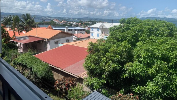 Un área residencial con casas, una masa de agua y un paisaje montañoso al fondo.