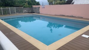 Una piscina rectangular rodeada por una terraza de madera.