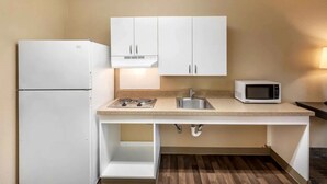 A compact kitchen with white cabinets, a built-in microwave, and a sink. -  Relax Suites Extended Stay - La Mirada (La Mirada)
