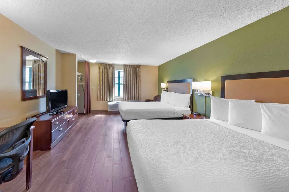 Une chambre d’hôtel avec deux lits, une télévision, un bureau et une chaise.