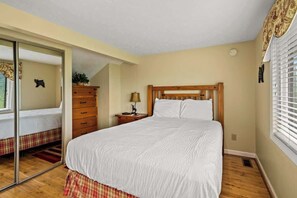 A bedroom with a bed, a dresser, a lamp, and a mirror.