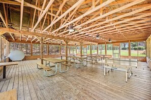 Un pavillon en bois abrité, équipé de tables de pique-nique et de ventilateurs de plafond.