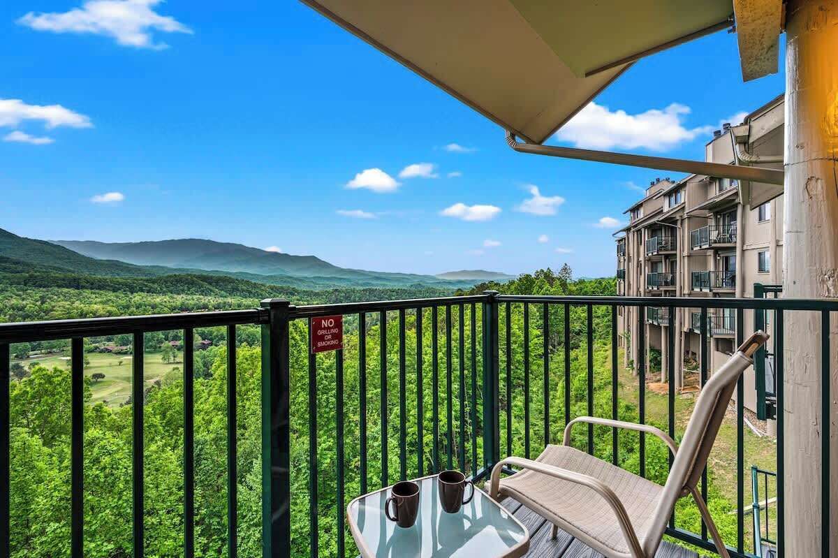 A balcony with a view of green hills and a "NO smoking" sign.