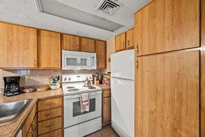Une cuisine avec des meubles en bois, une cuisinière blanche, un four à micro-ondes et un réfrigérateur.