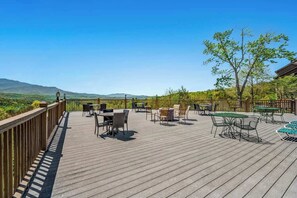 Une terrasse en bois avec des sièges extérieurs et une vue sur les montagnes.