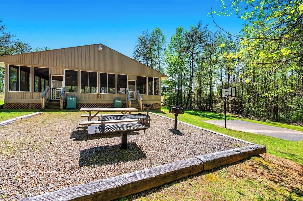 Een lodge met een overdekt terras, picknicktafels en een afvalbak.