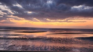 Ein Strand mit Sonnenuntergang und bewölktem Himmel.