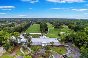 A golf course with a clubhouse, parking area, and surrounding greenery.