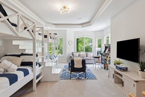 A modern living room with a bunk bed, a sofa, a TV, and a gaming console.
